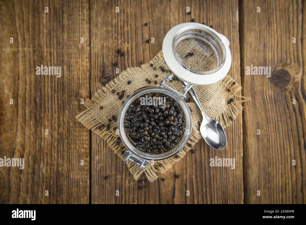 Black Peppercorns preserved on wooden background, selective focus, close-up shot Stock Photo