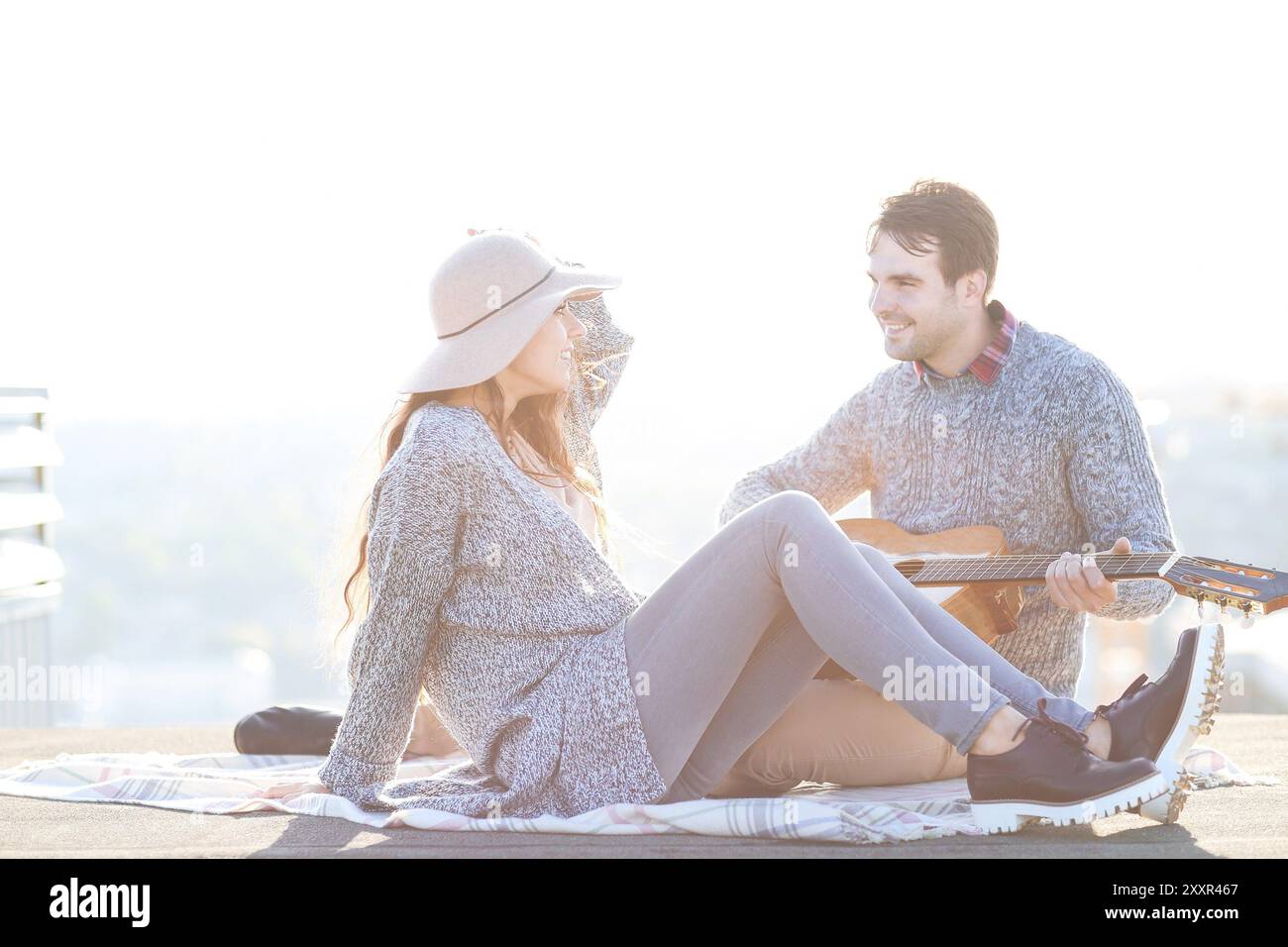 Young man and woman with guitar having fun outdoors Love and relations concept Stock Photo