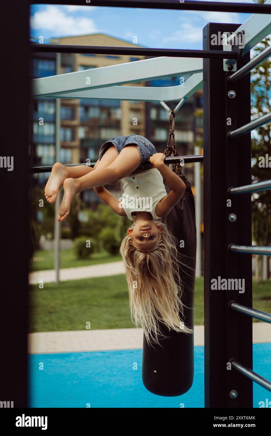 Young girl hangs upside down at playground Stock Photo - Alamy