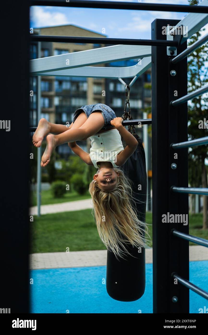 Young girl hangs upside down at playground Stock Photo - Alamy