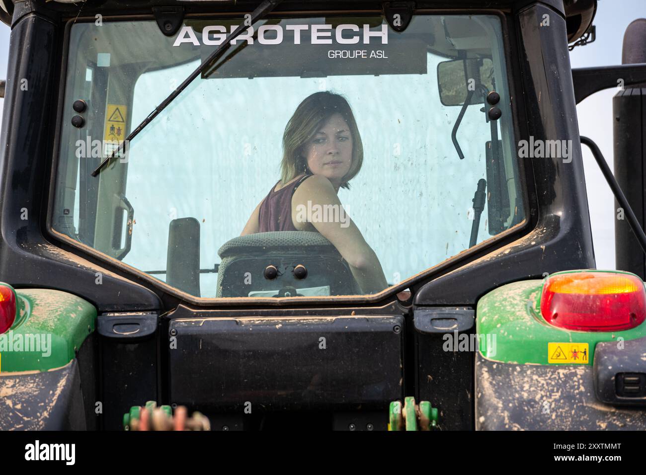 Woman, farmer driving a tractor in a field. Farm work, feminization of agricultural professions Stock Photo