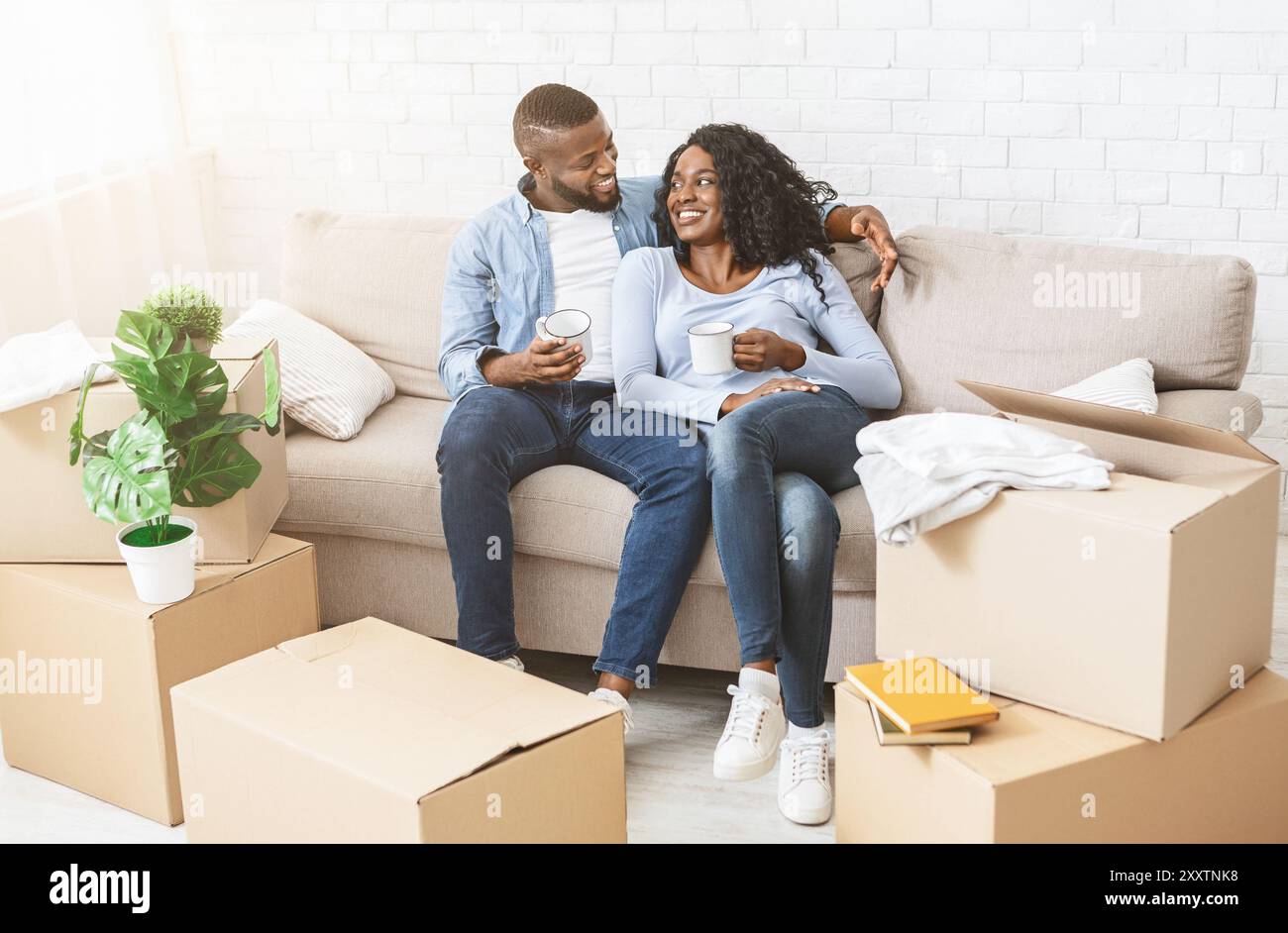 Happy couple taking break, unpacking on moving day Stock Photo