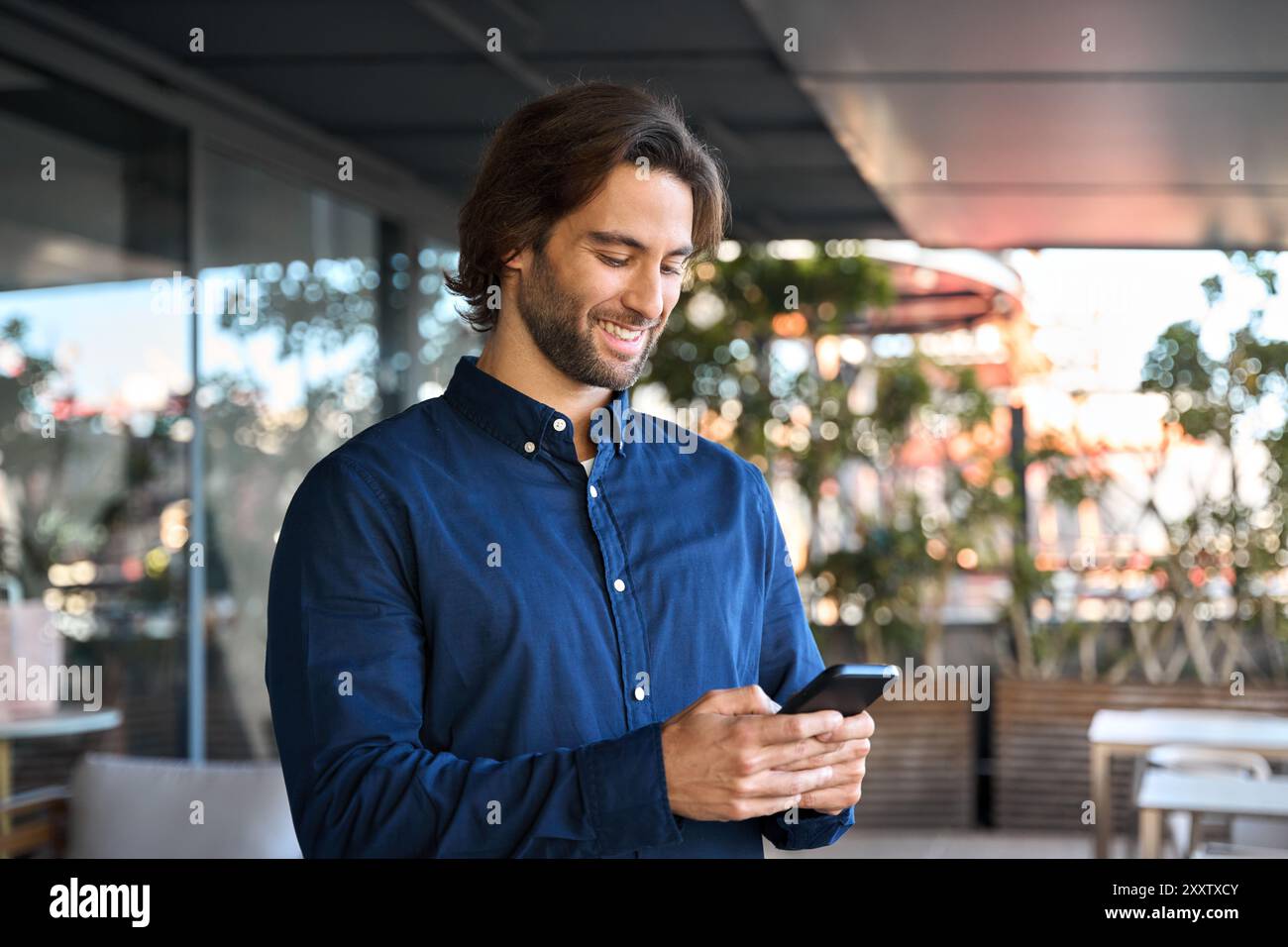 Happy young business man using mobile phone standing outdoors. Stock Photo