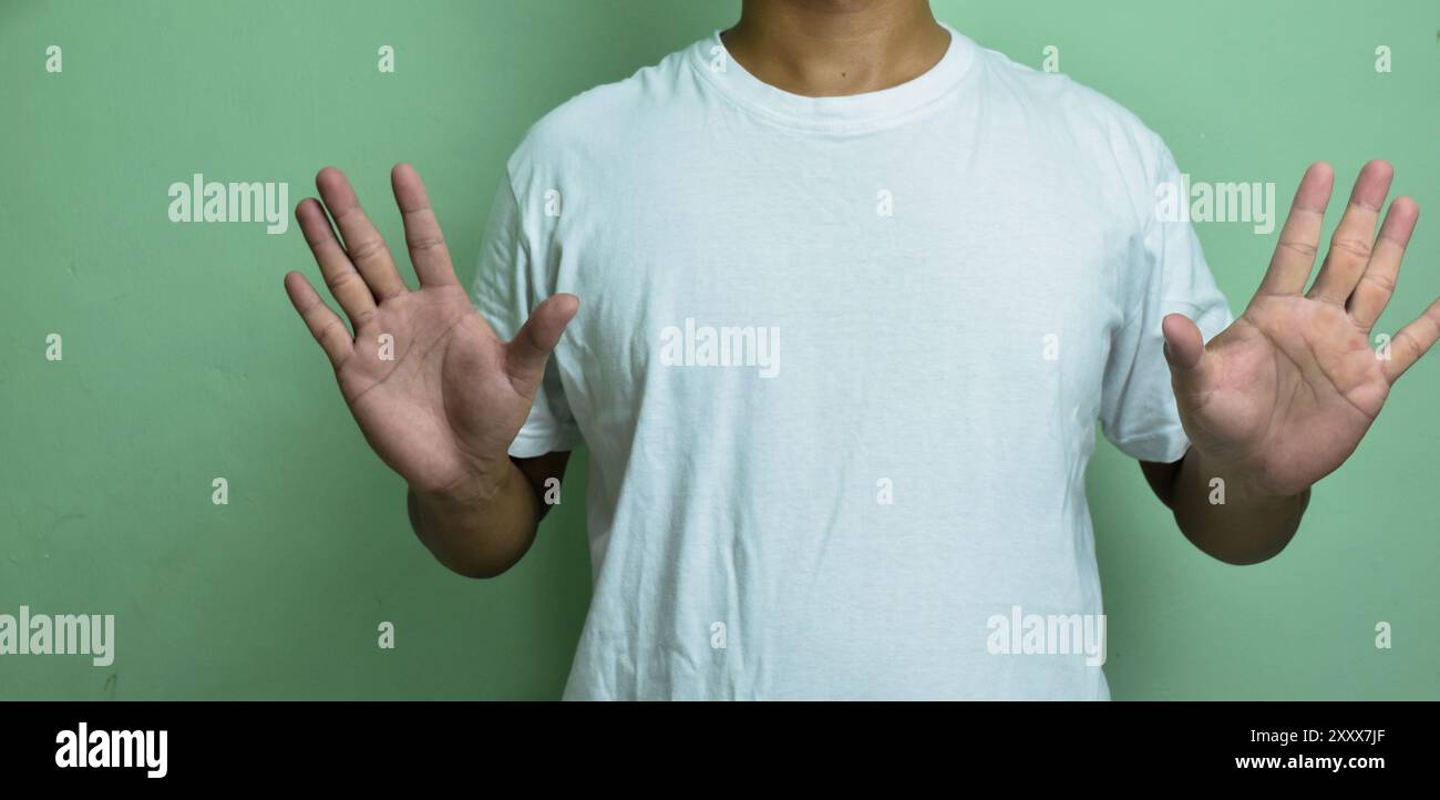 young deaf mute man using sign language on green background Stock Photo