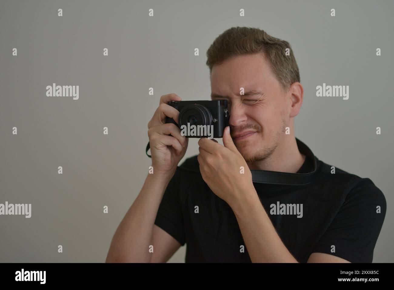 Young man with a photocamera. The photographer uses a camera to take a photo looking through lens. Professional photographing concept. Stock Photo