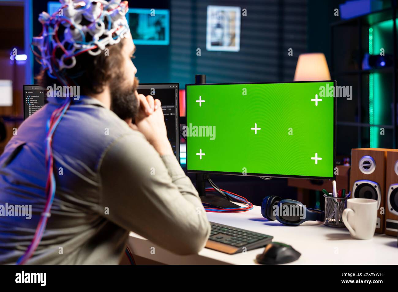 Neuroscientist using EEG headset to upload his mind into green screen computer, attaining immortality. Software developer using mockup PC, experimenting with transferring consciousness into cyberspace Stock Photo