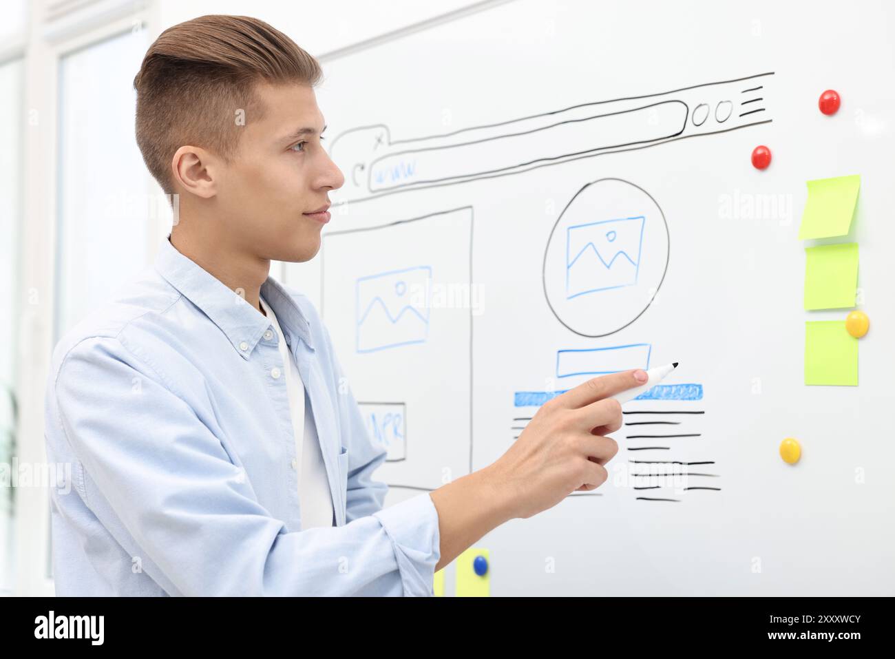 Developing UI design. Man drawing website wireframe on whiteboard indoors Stock Photo