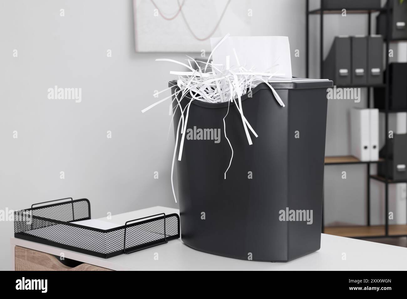 Destroying sheet of paper with shredder on white table in office Stock ...