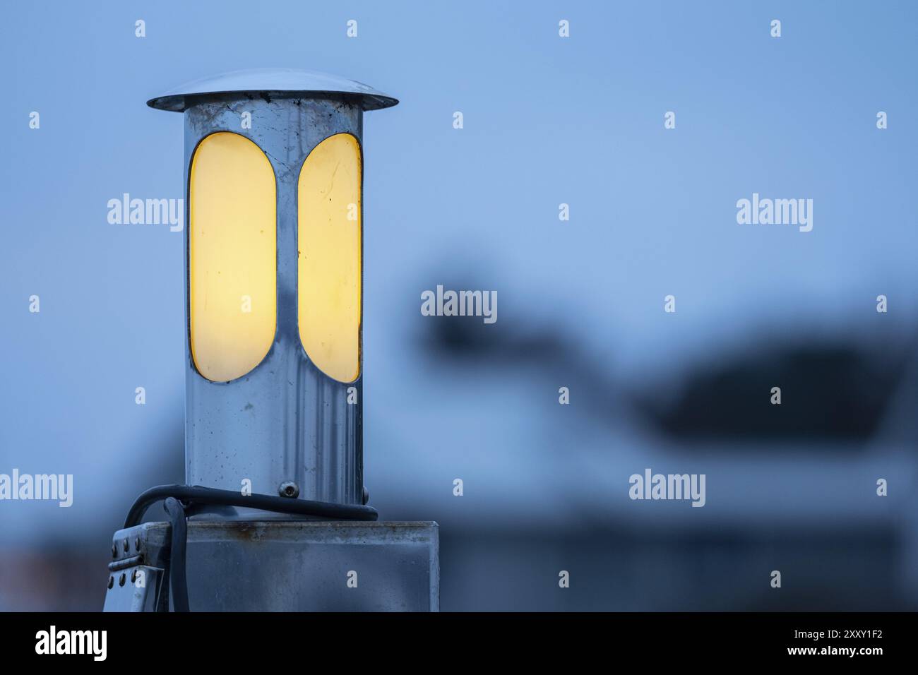 Circular lamp shining yellow in the dusk Stock Photo