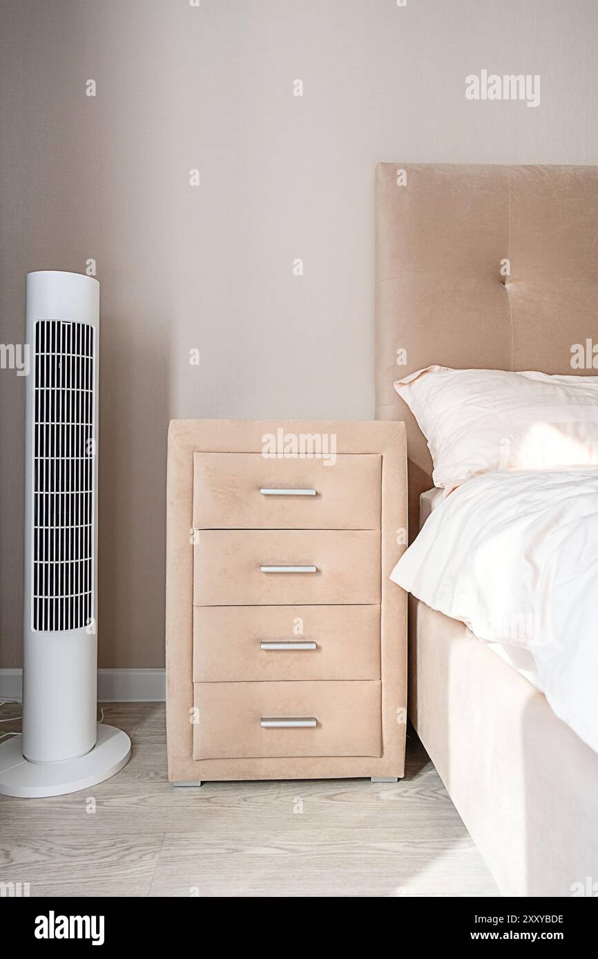 White tower fan next to bedside table in light modern bedroom Stock ...