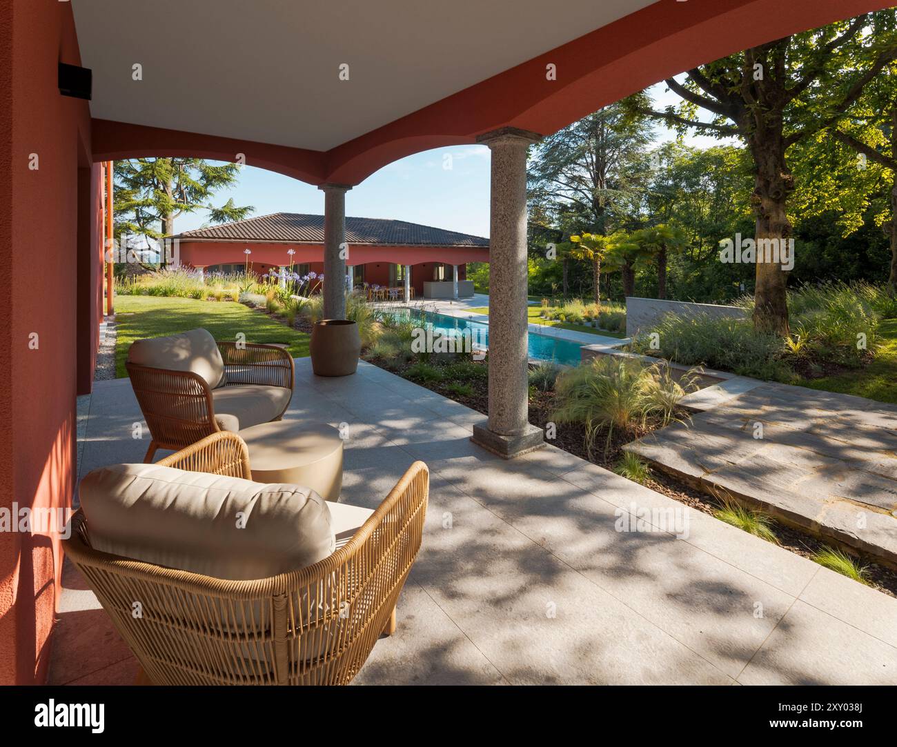 Outdoor patio of a villa, furnished with two outdoor armchairs and a small table, perfect for relaxing. In the background you can see the outbuilding Stock Photo