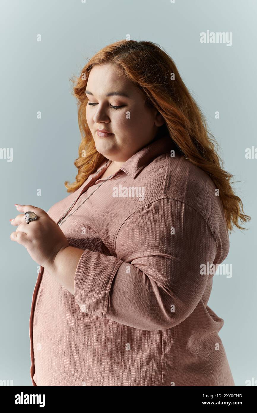 A woman in a pink shirt looks down thoughtfully. Stock Photo