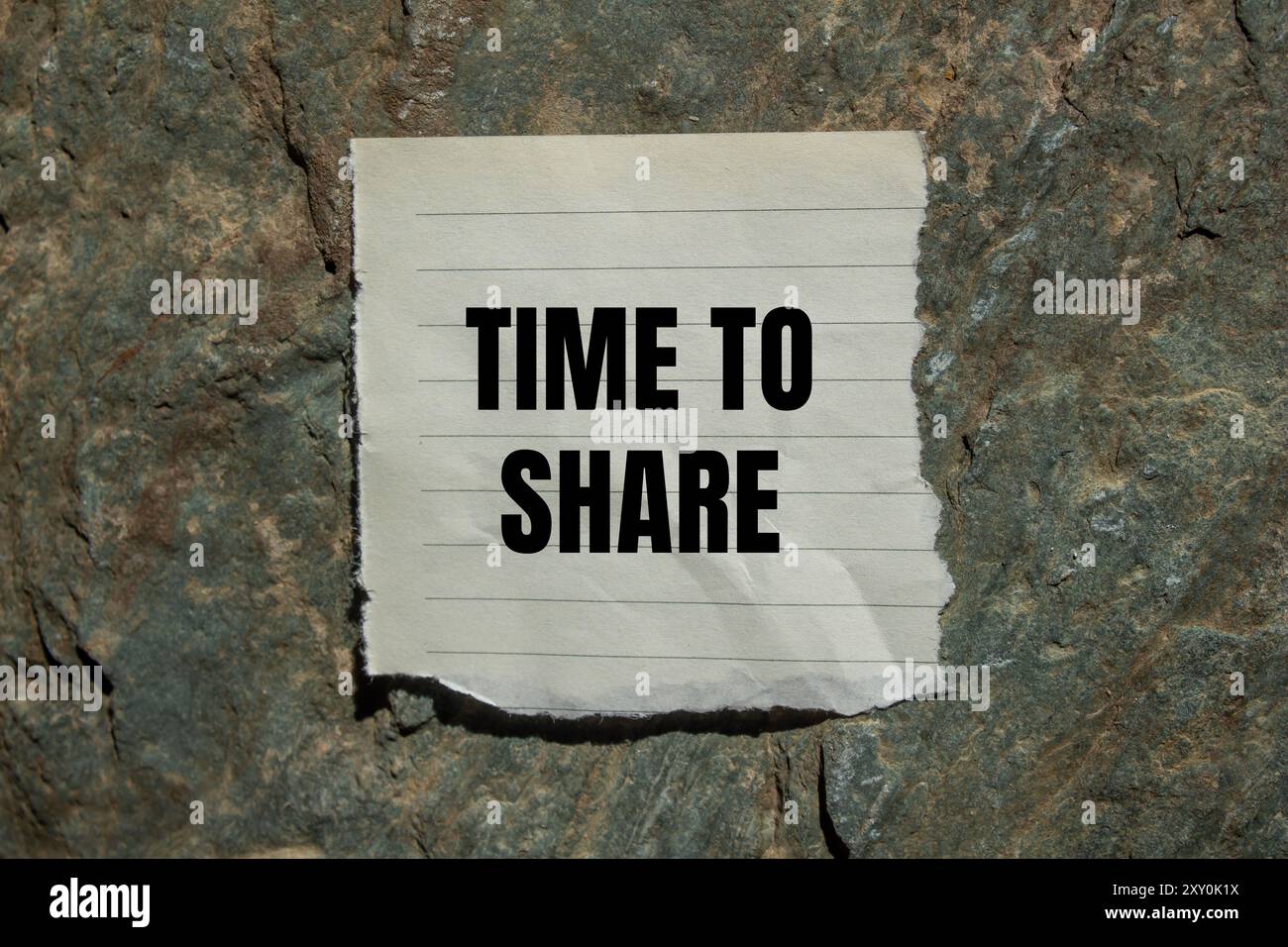 Time to share message written on ripped torn paper piece with stone ...