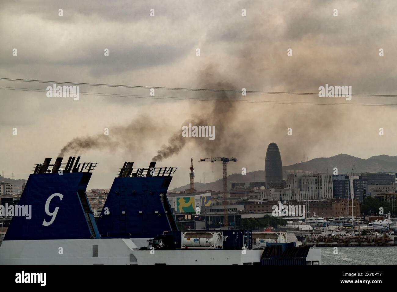 A ferry ship's funnels give off smoke while heading the port of Barcelona. Sulphur dioxide and nitrogen oxide emissions makes Barcelona port worst in Europe for air pollution mainly for cruise ships action. Stock Photo