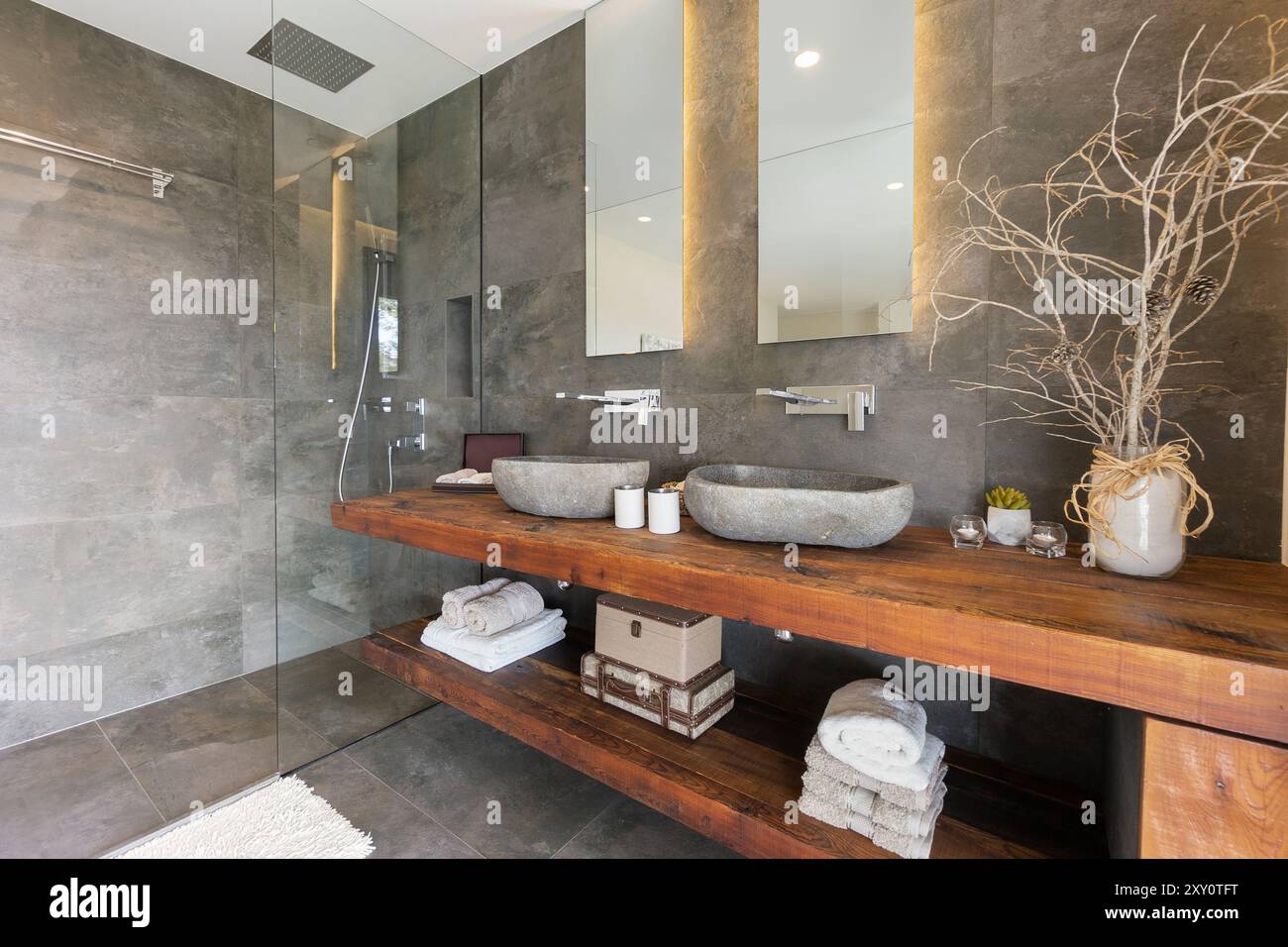 A contemporary bathroom with stone textured walls, wooden vanity with two  stone sinks, mirrors and a glass-enclosed shower area Elegant decor and  natu Stock Photo - Alamy, image size:1300x956