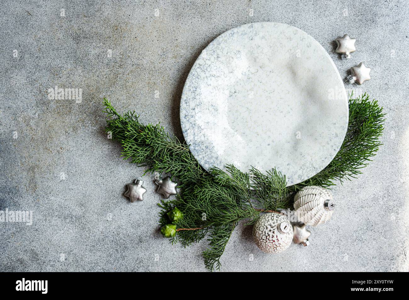 Top view of a festive composition with Christmas decorations, including pine branches and ornaments placed strategically on a textured concrete backgr Stock Photo