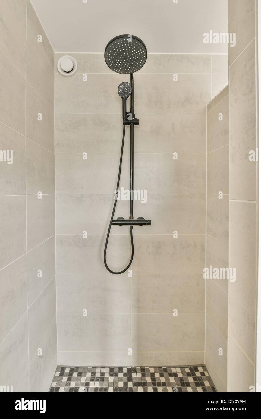 Modern shower with a large overhead and handheld showerheads in a clean, tiled bathroom. Stock Photo