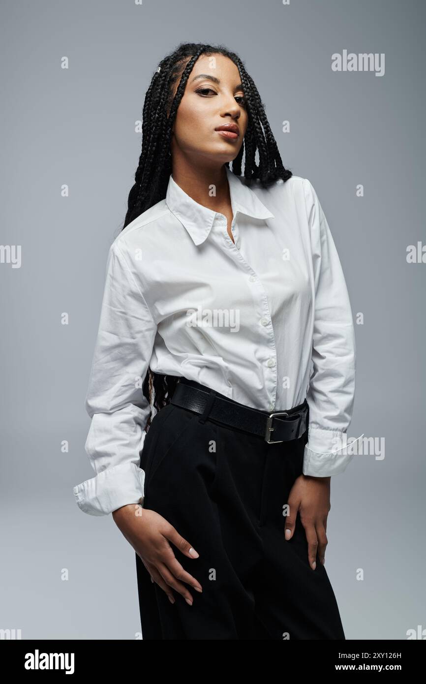 A young African American woman with braids poses in a white button-down ...