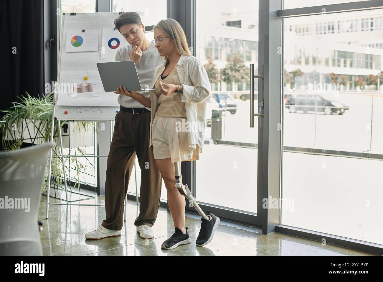 Two colleagues work together on a laptop, reviewing charts and graphs. Stock Photo