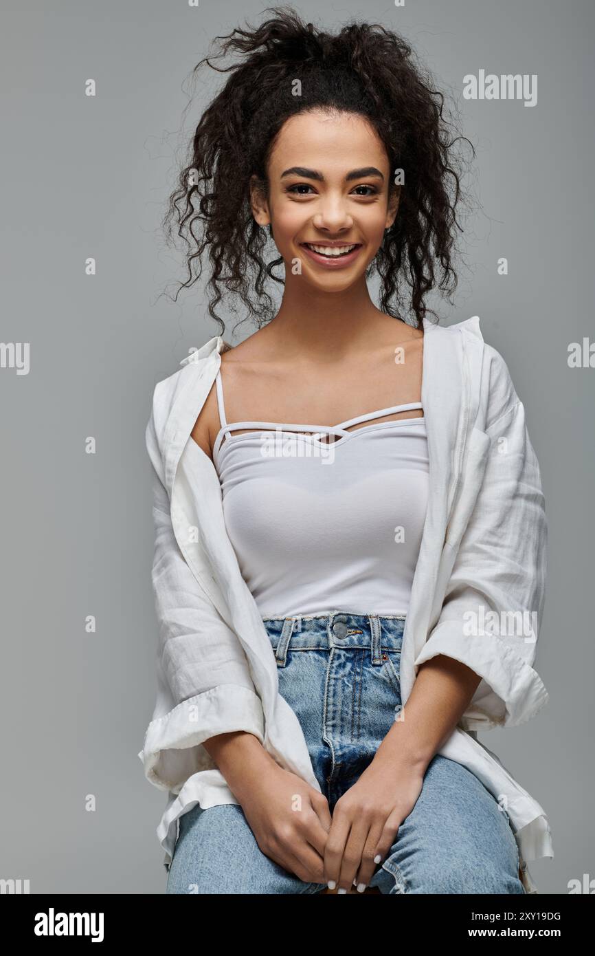 A young African American woman with curly hair smiles brightly as she ...