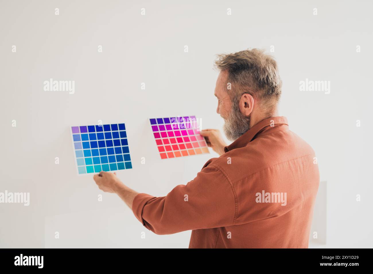 Photo of senior male hold compare choose color paint wall dressed brown ...