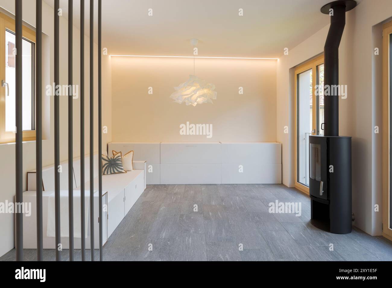 Front view of a living room furnished with cardboard furniture and sofa for home staging. On the right is a black stove. No one inside Stock Photo