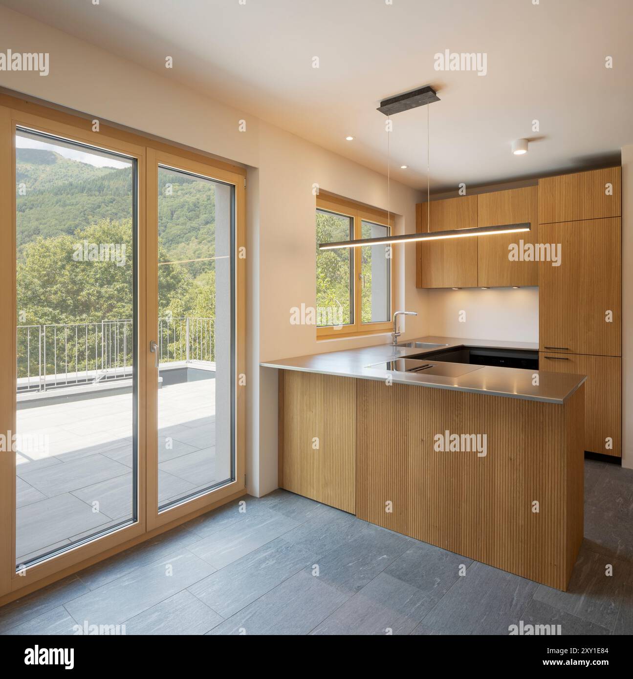 Front view of a modern wooden kitchen with an open door and an induction  hob. Above the island is a suspended chandelier and spotlights. No one  inside Stock Photo - Alamy, image size:1295x1390