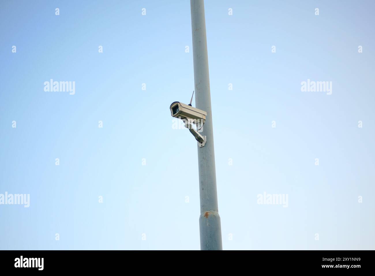 security camera hanging on power pole isolated on blue background Stock Photo