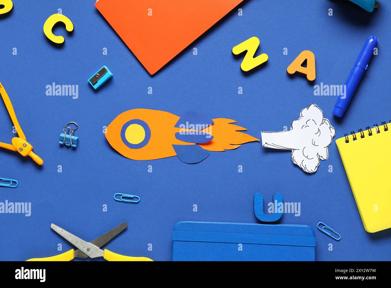 Paper rocket with smoke and different school stationery on blue ...