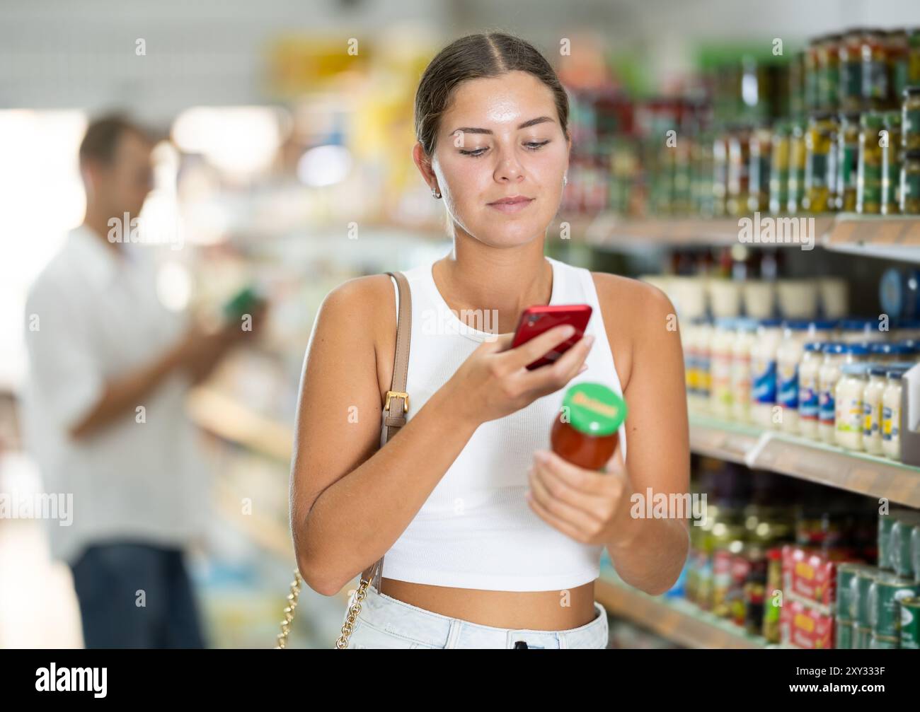 Girl scanning barcode or qr code with smartphone on sauce label in ...