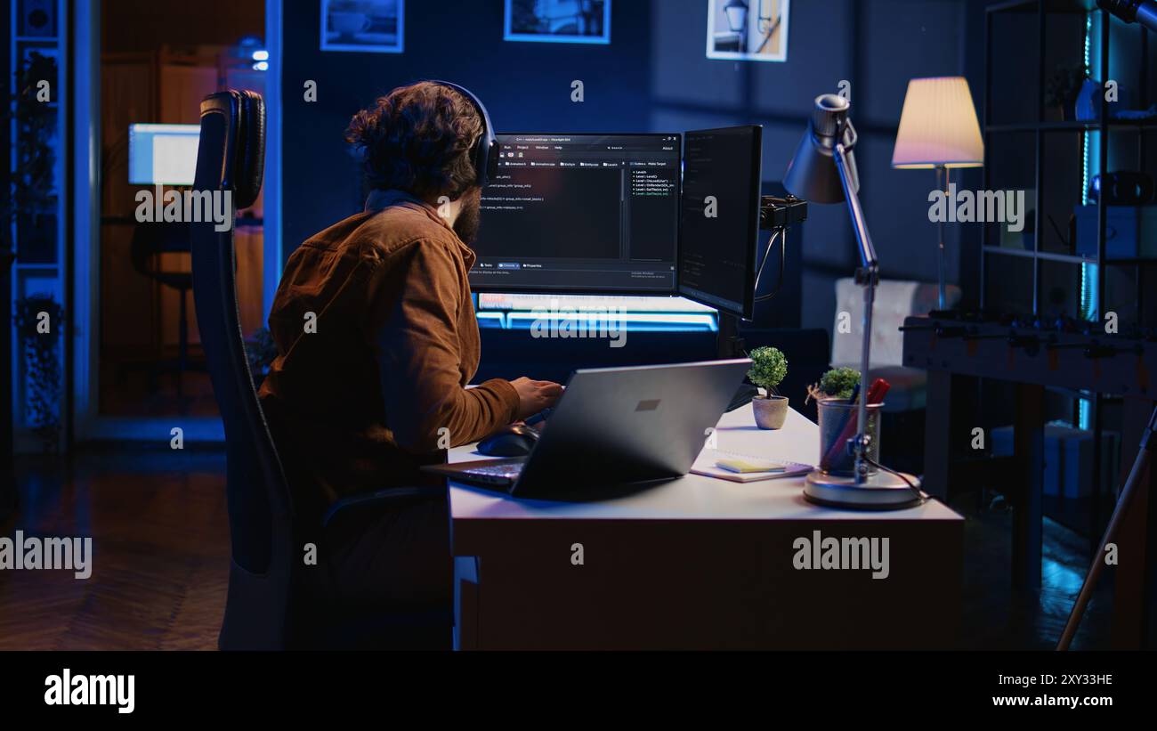 Hyperactive software developer suffering from adhd affliction, writing code, drinking coffee, listening music, arranging desk objects. Distracted IT admin doing multitasking in home office, camera B Stock Photo