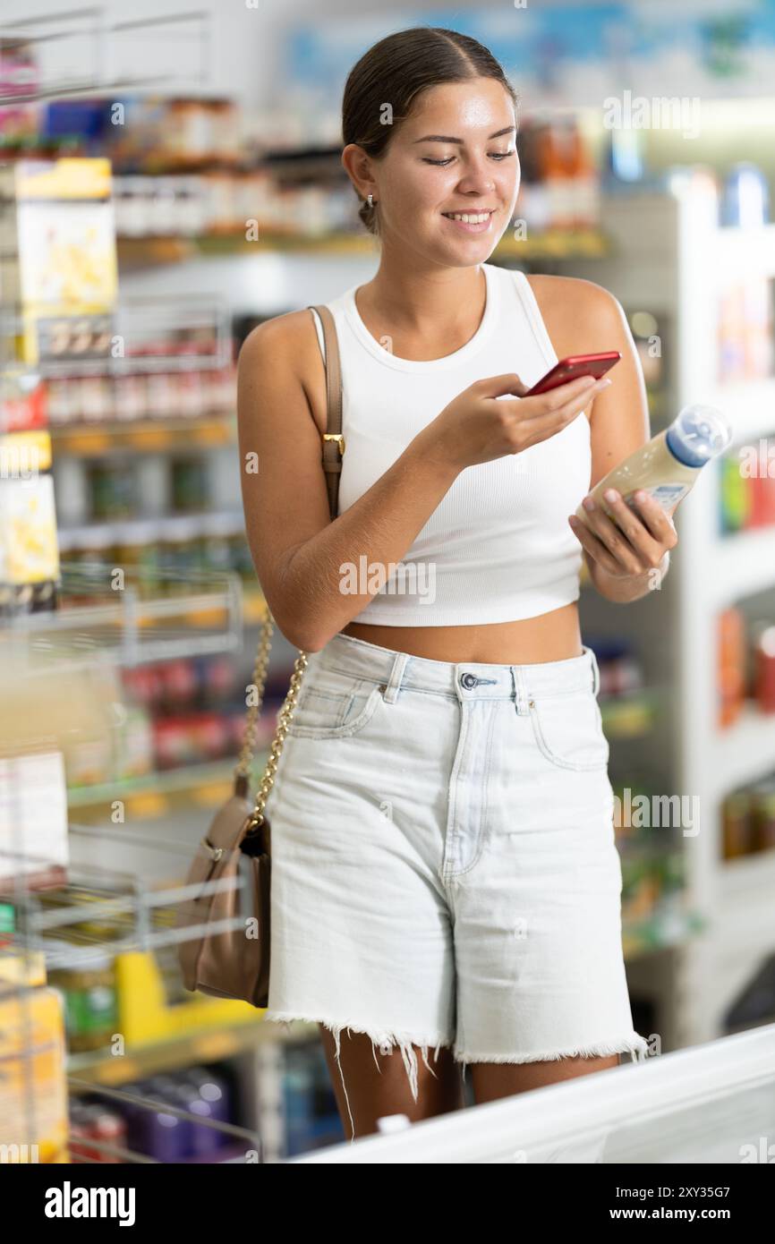 Girl scanning barcode or qr code with smartphone on mayonnaise label in ...