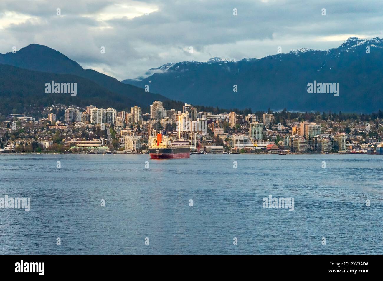 Vancouver, BC, Canada - April 26, 2024: A cargo ship traveling in Vancouver Harbour with North Vancouver in the background. Stock Photo