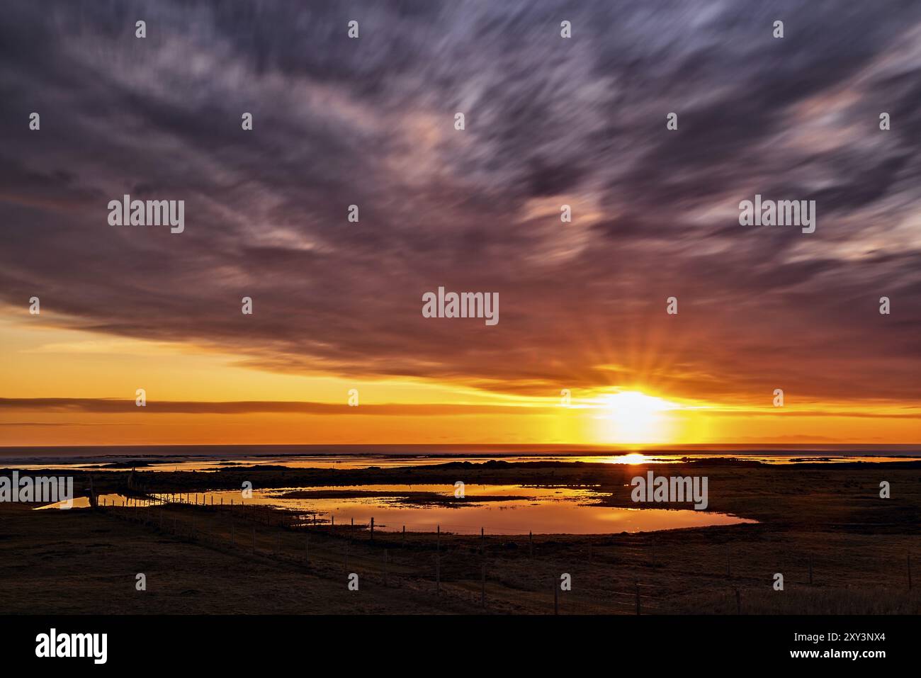 Majestic sunset with clouds in moviment reflected in the water Stock Photo