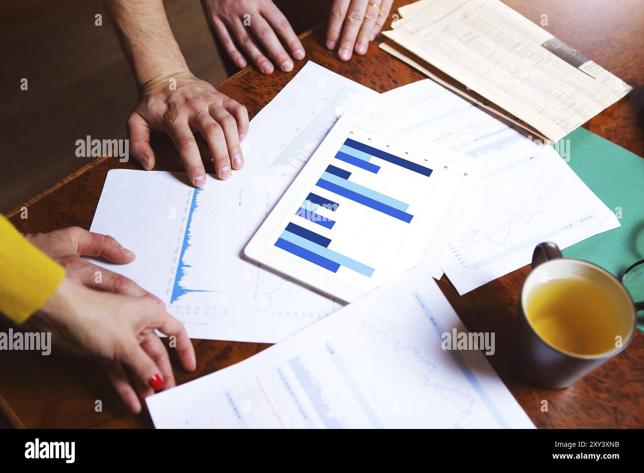 Business team hands at work with financial reports and a tablet computer, top view Stock Photo