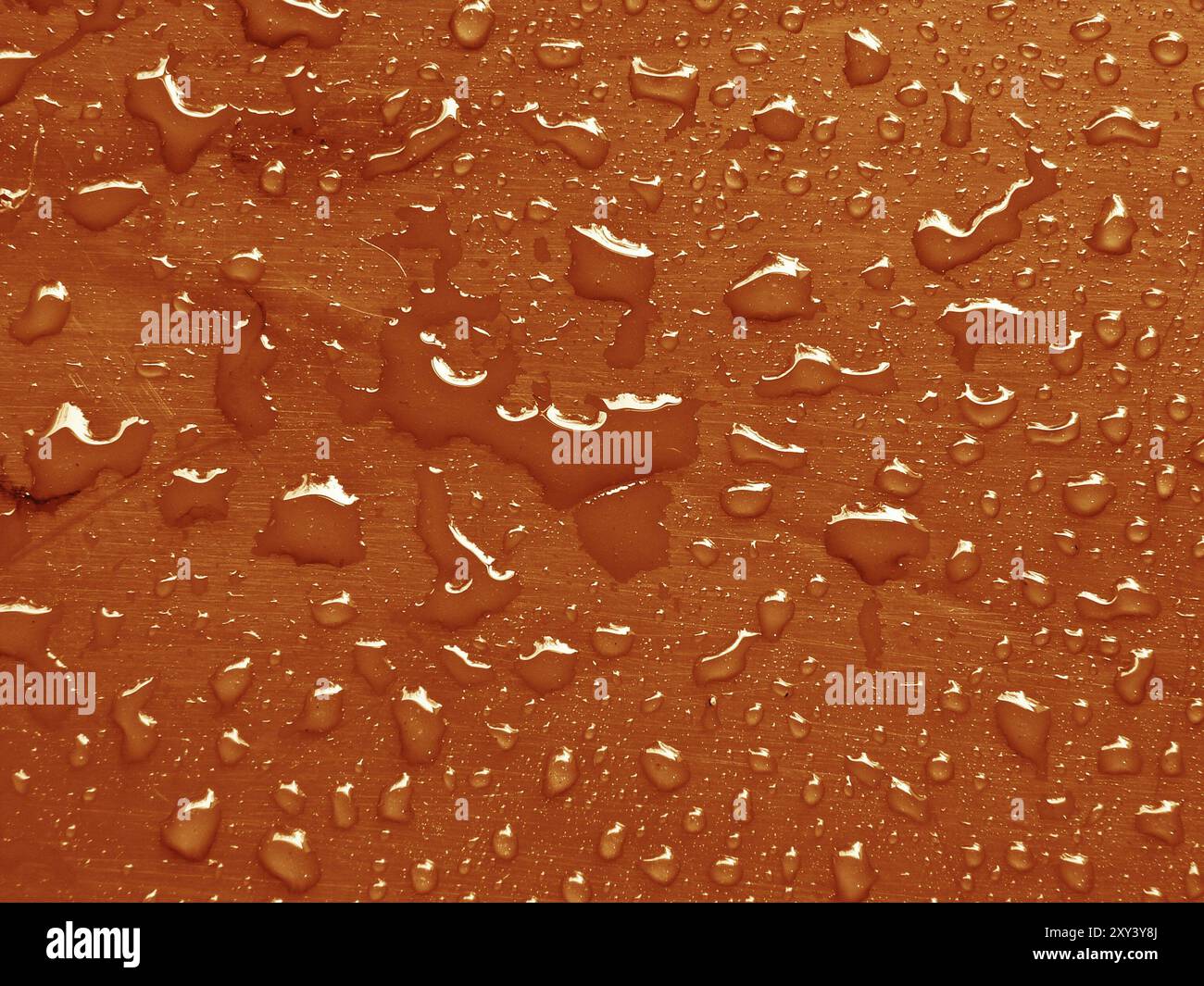 Water drops on russet orange colored metallic surface Stock Photo