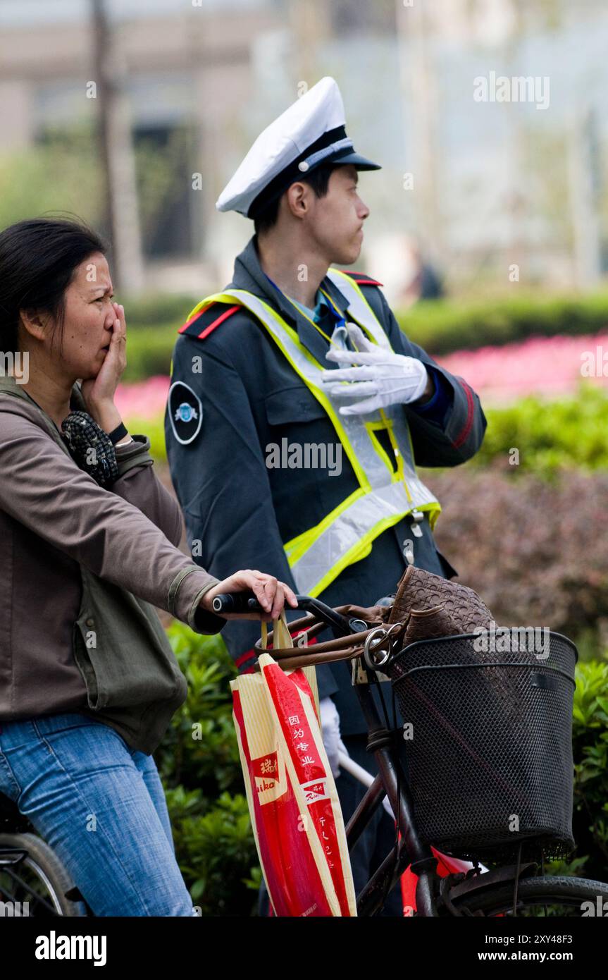 A traffic volunteer helping control the flow of bicycles and cars through Xinjieko junction in Nanjing, China. Stock Photo