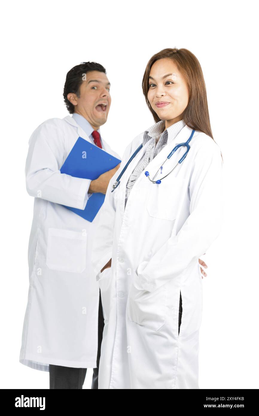 A pretty Asian female, hispanic male doctors having fun joking around making silly, goofy, funny facial expressions showing sense of humor. Focus on f Stock Photo