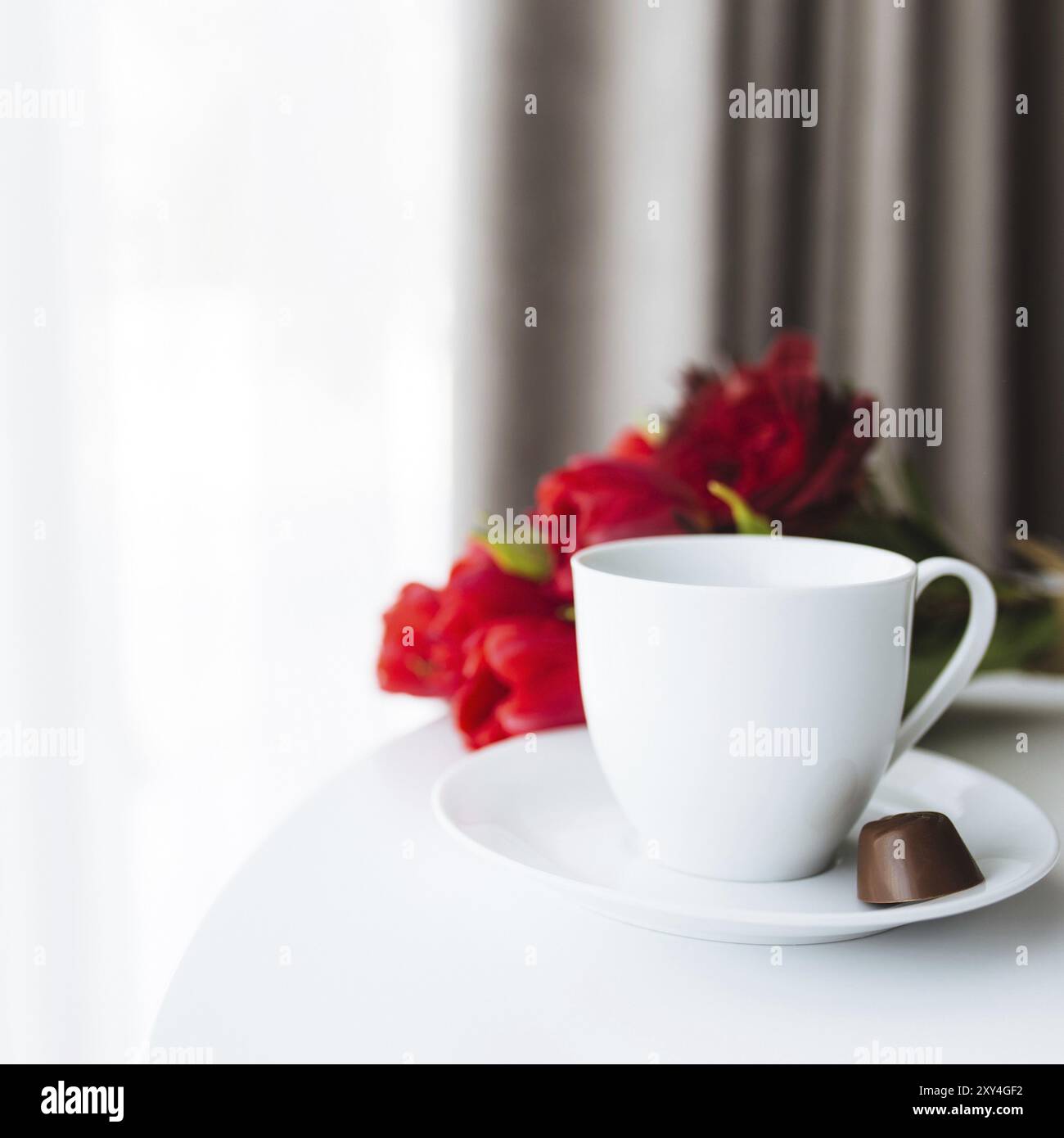 Red tulips bouquete on table, white coffee cup. Concept for greeting card for mothers day, international womans day or valentines day concept, birthda Stock Photo