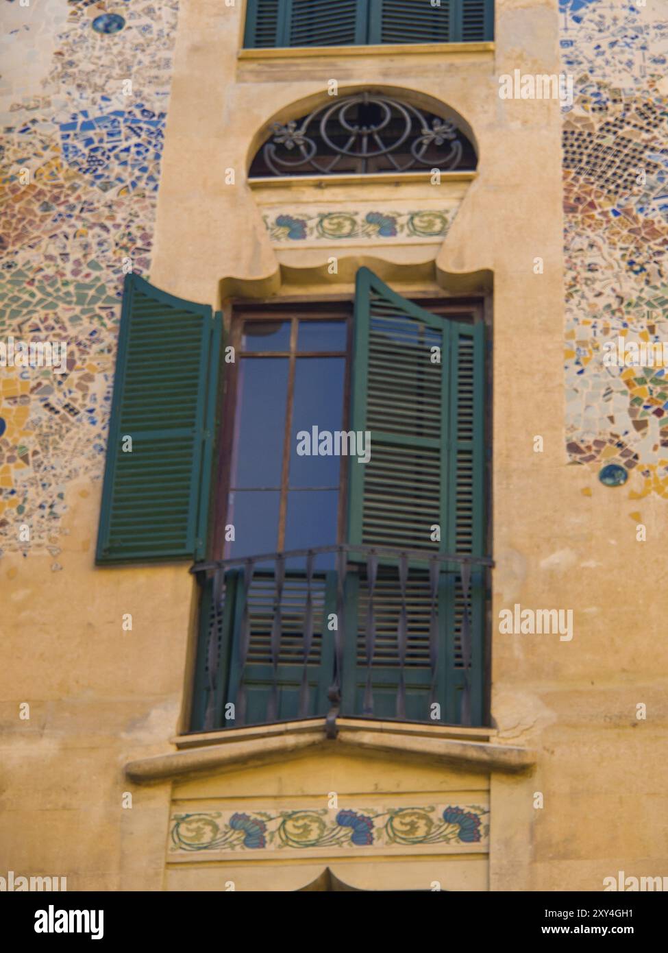 A close-up of a window with open green shutters and artistic mosaics on ...