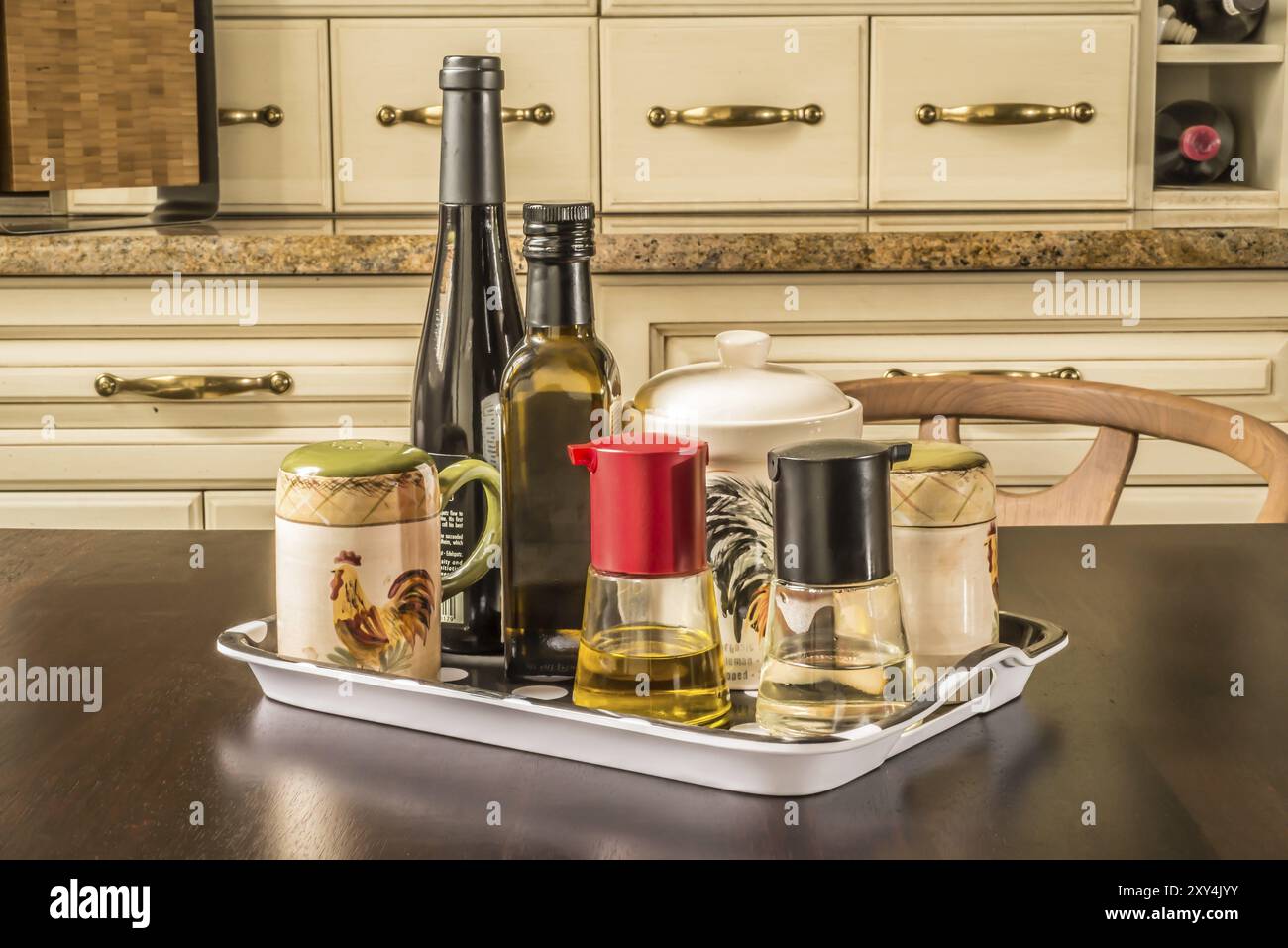 Assorted condiments on a tray at a table inside a private house whith french style classical kitchen cupboards in the background Stock Photo