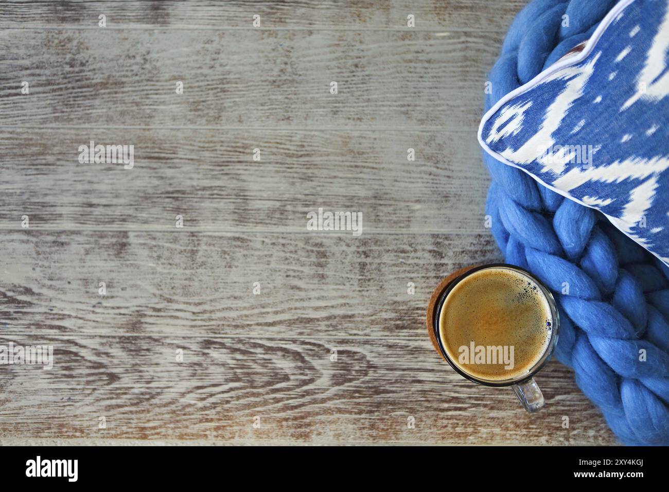 Blue pillow with blanket and cup of coffee on the wooden background. Close up Stock Photo
