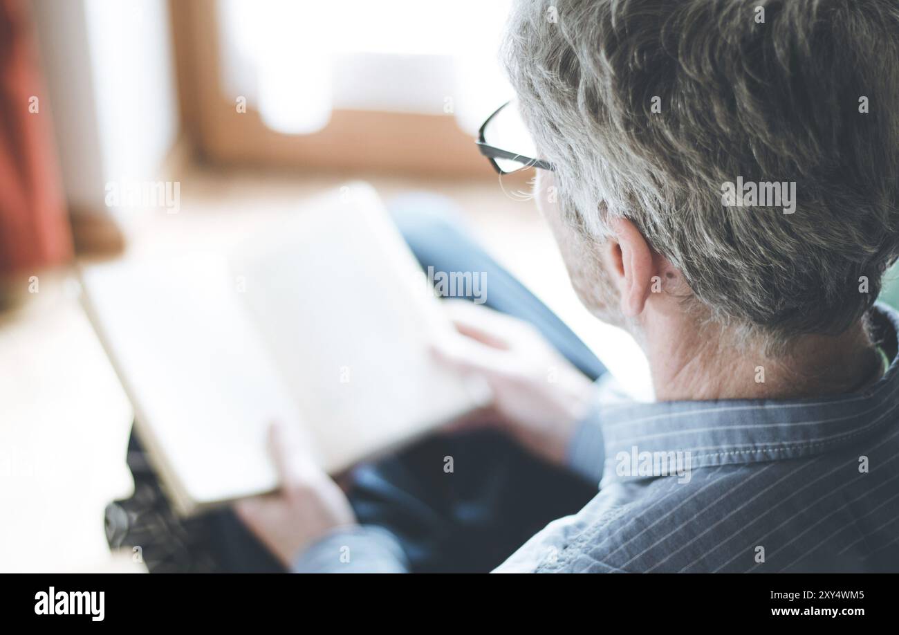 Cut out picture of a senior man who is reading a book at home Stock Photo