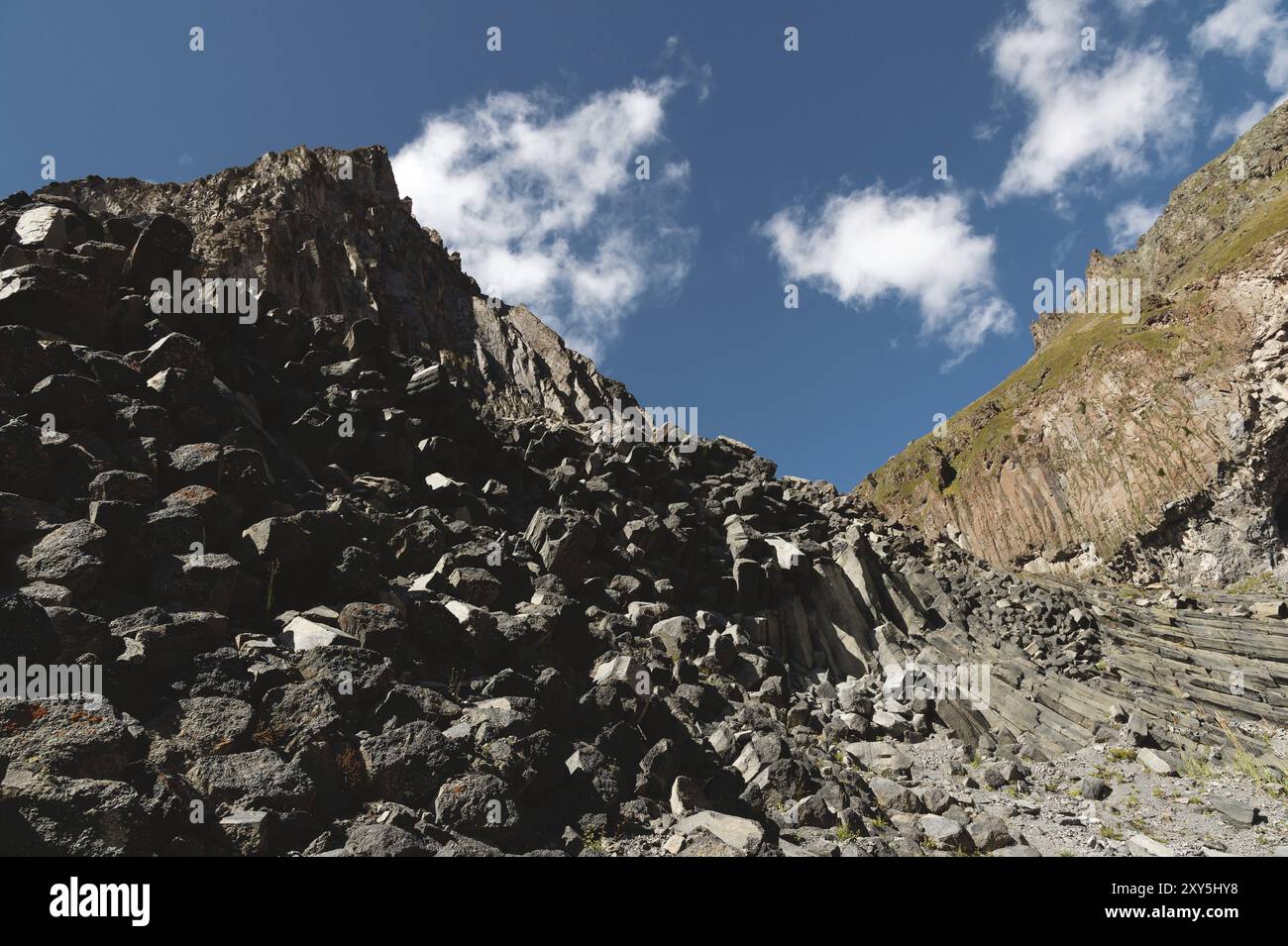 Wide angle view of a rocky slope on a sunny summer day. Structural hexagonal cliffs in the North Caucasus Stock Photo