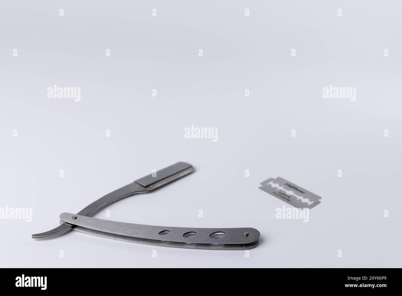 An open barber’s straight razor with a gleaming blade, set against a ...