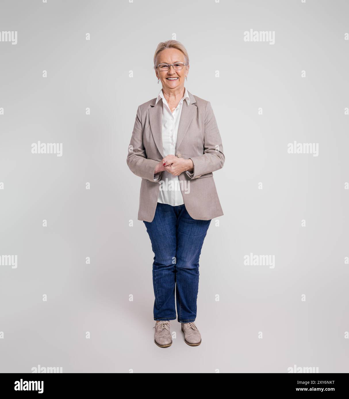 Portrait of smiling confident senior businesswoman with hands clasped standing on white background Stock Photo