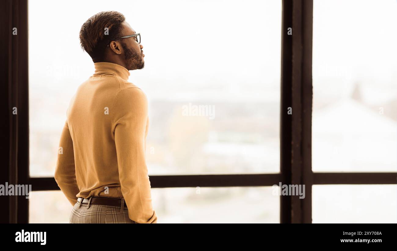 Single afro businessman looking out the window Stock Photo