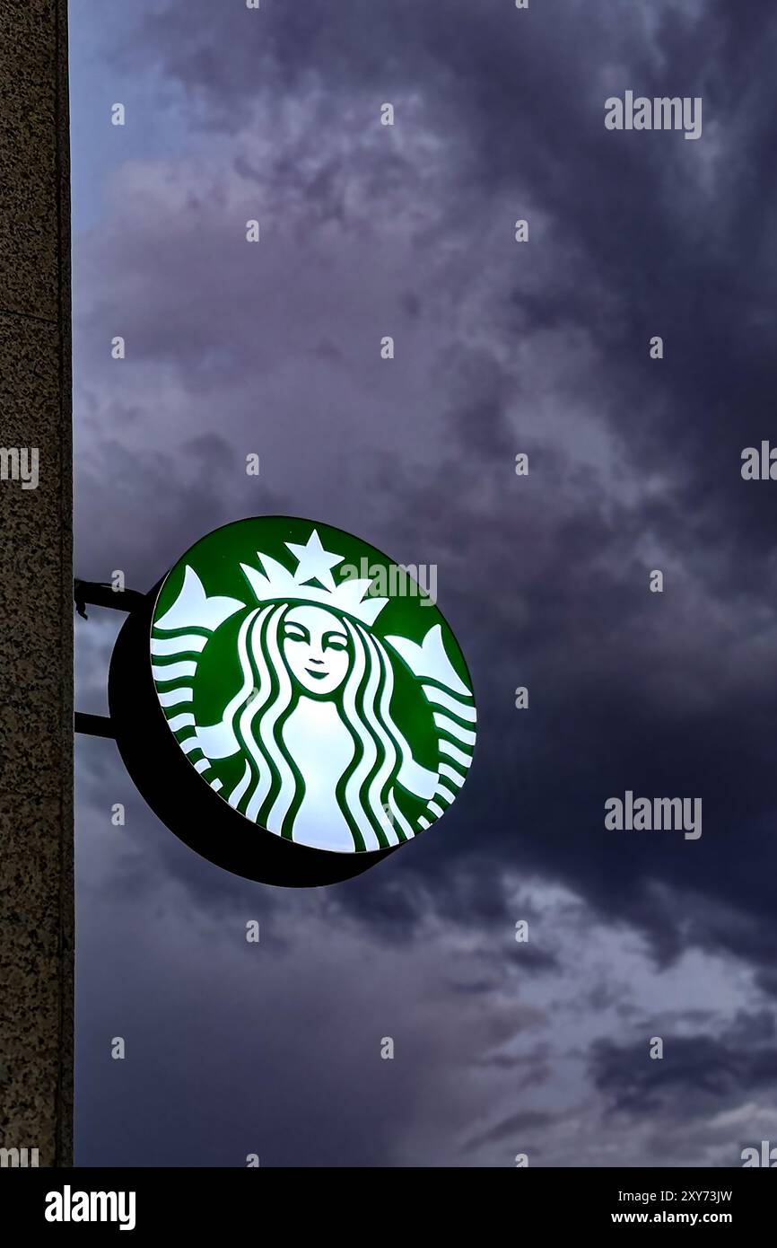 The sign of the Starbucks coffee shop glows at dusk. Almaty, Kazakhstan on July 26, 2024 Stock Photo