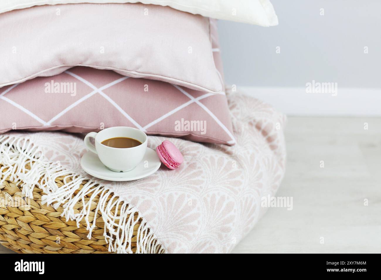 Pink and white pillows and cup of coffee and macaron on the wall background. Close up Stock Photo
