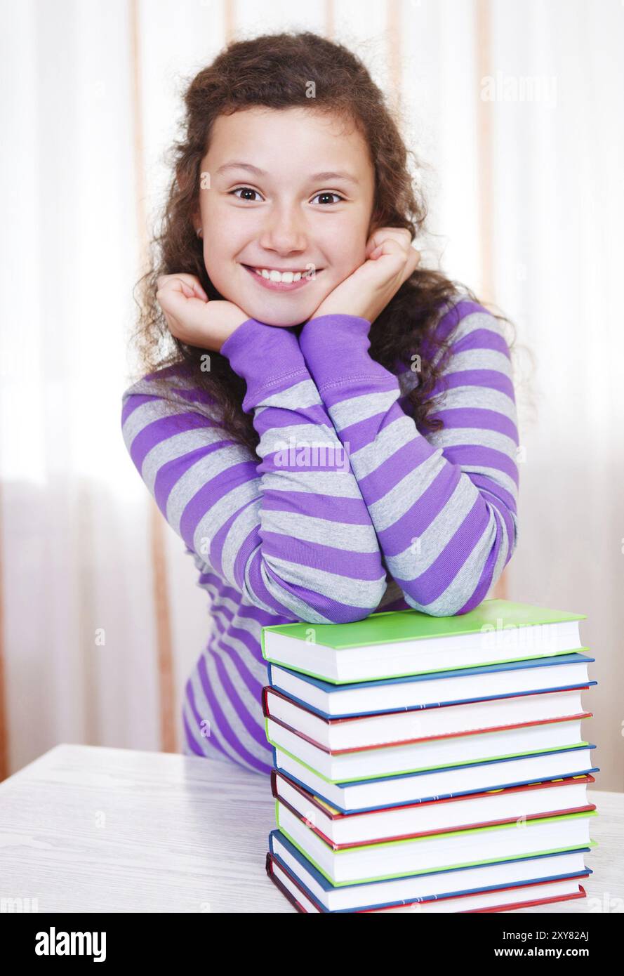 Little brunette smiling girl with pile of books Stock Photo - Alamy